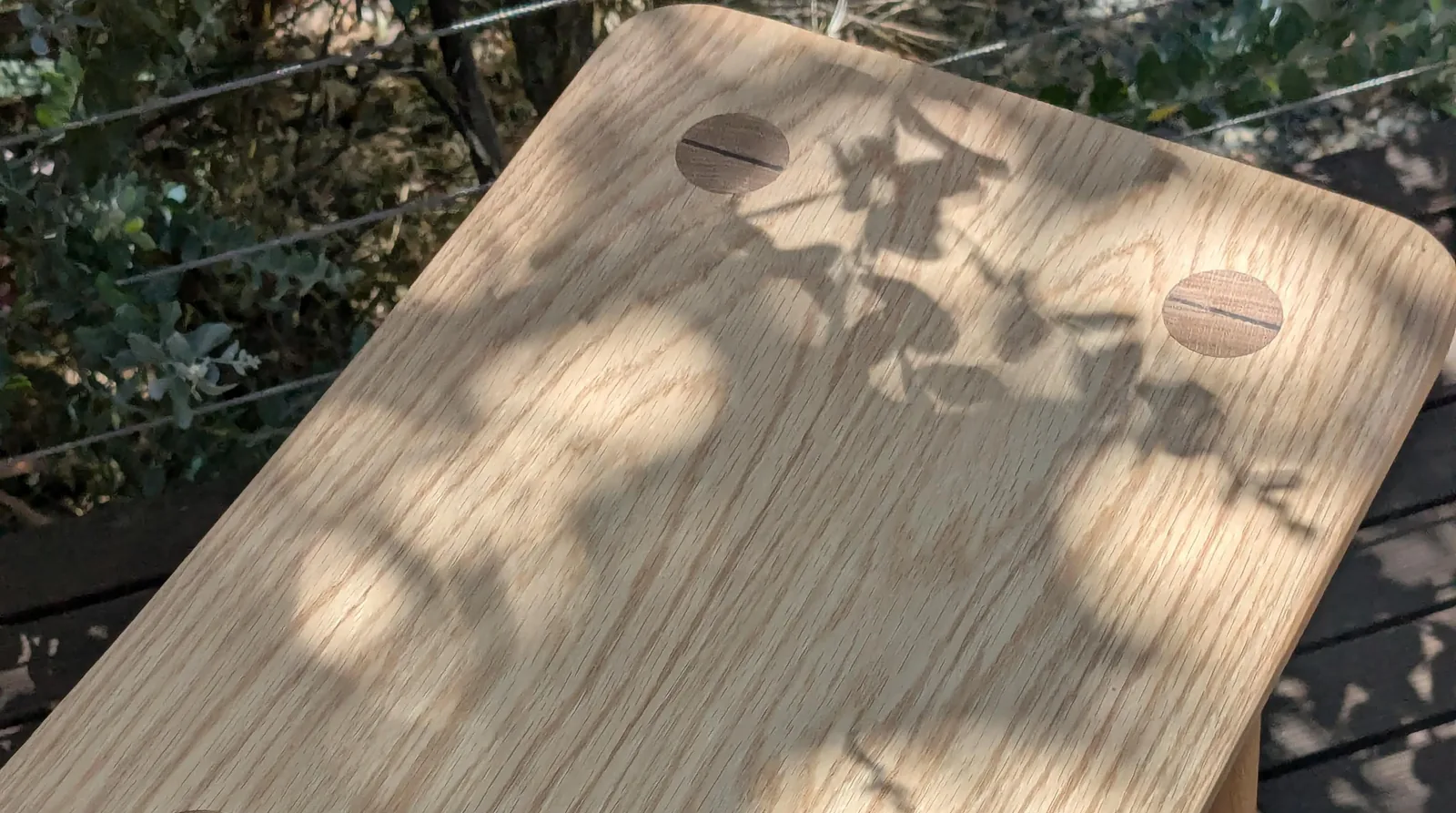 A solid oak stool showing wedged through-tenon joinery in the seat