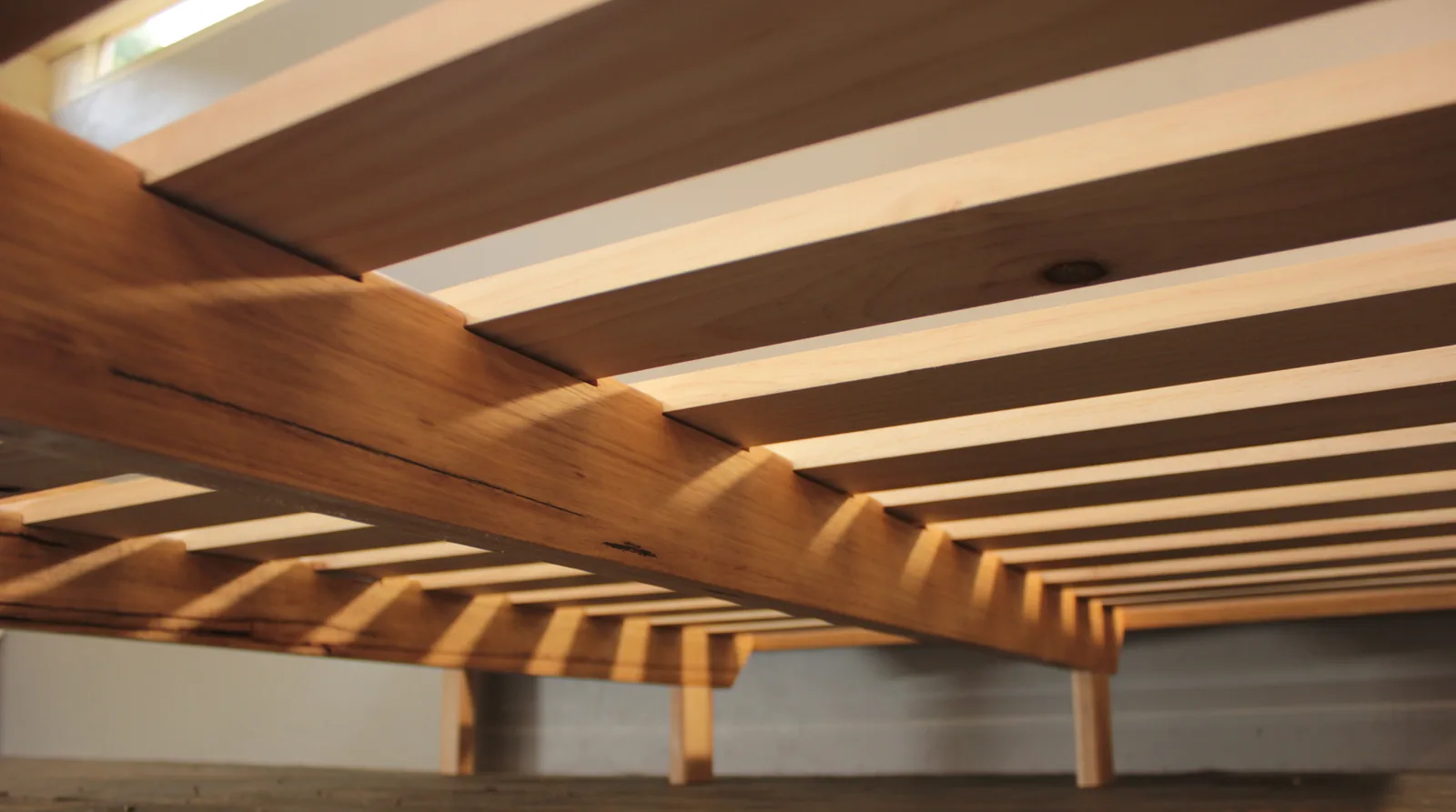 The underside of a solid timber bed frame showing its slat supports