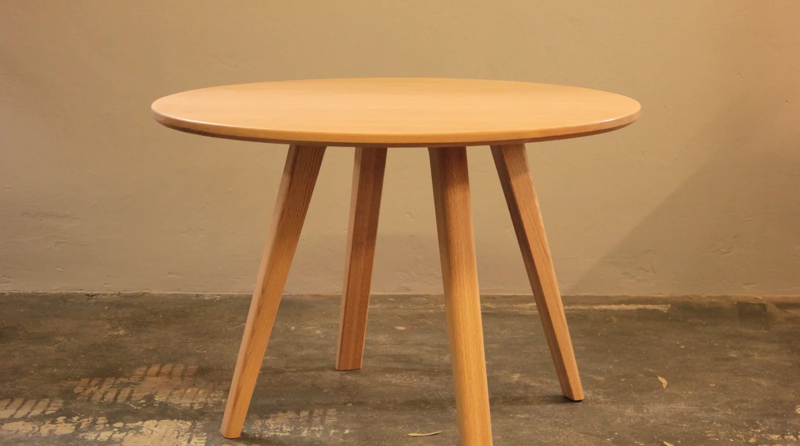 A round solid timber dining table with four tapered legs