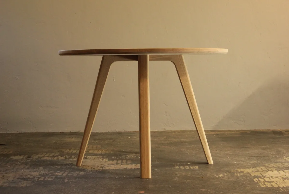 A round solid timber dining table with tapered splayed legs