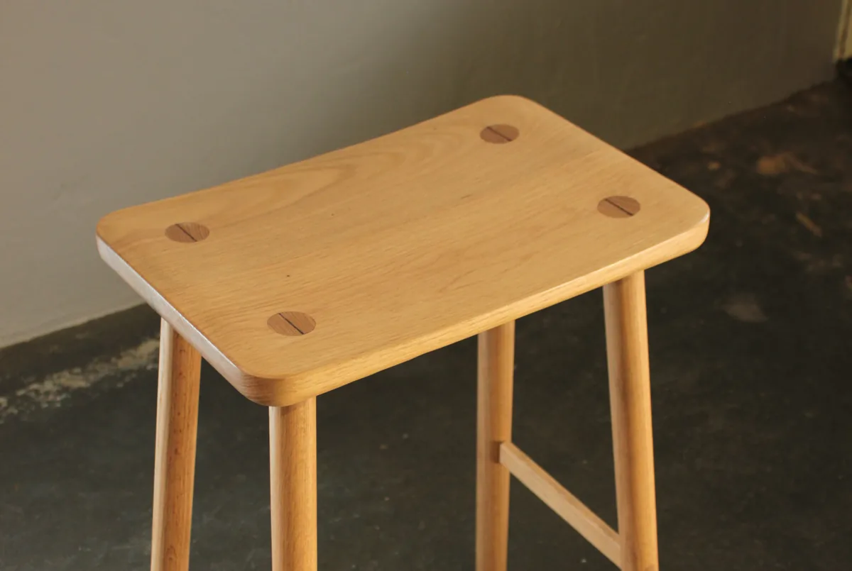 The underside of a solid timber stool showing wedged through-tenon joinery